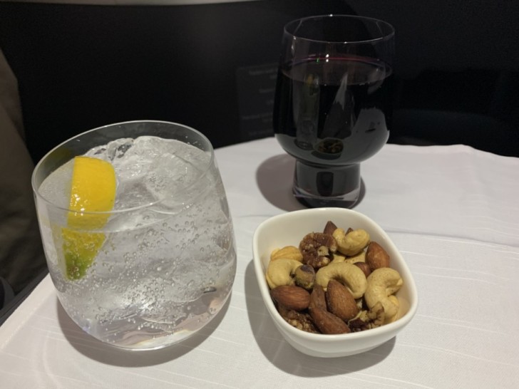 a bowl of nuts and a glass of water with a lemon wedge