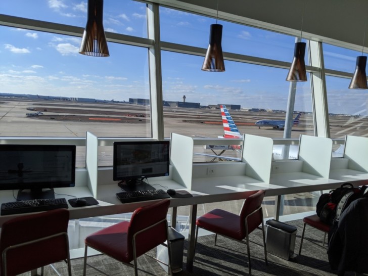 a desk with computers in front of a window
