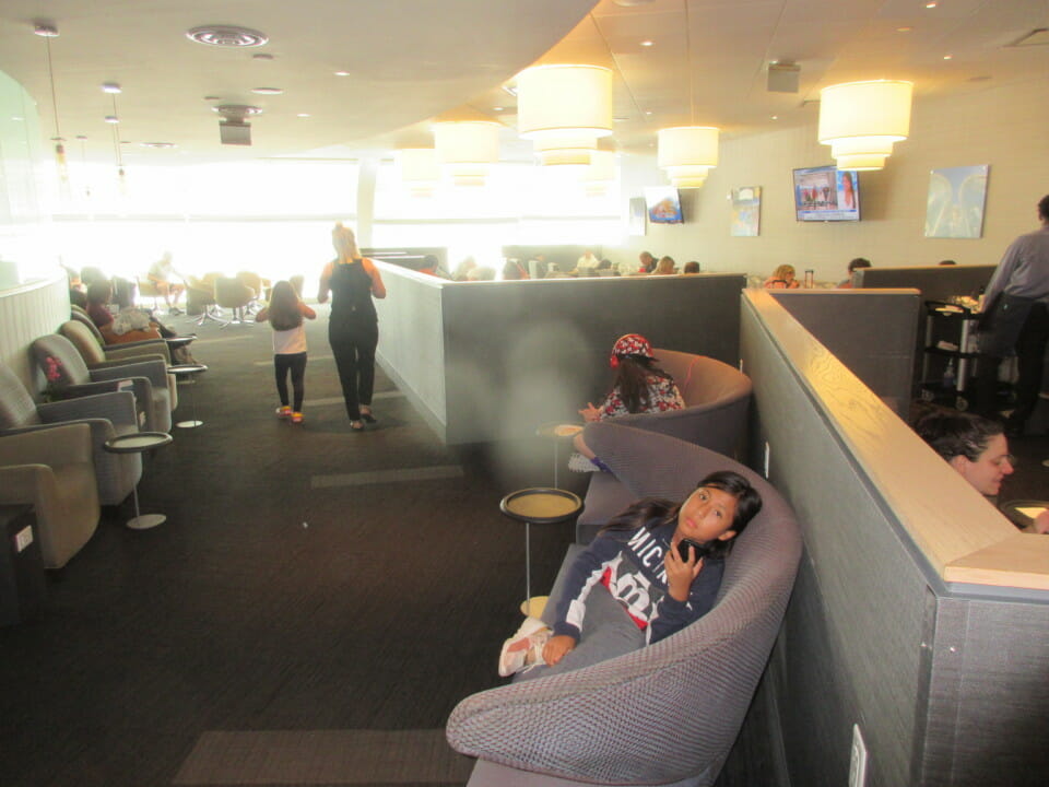 a girl sitting on a couch in a room with people