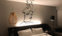 a bed with a lamp and a face on the wall