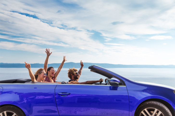 a group of people in a blue convertible car