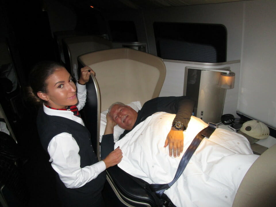 a woman standing next to a man lying in a bed