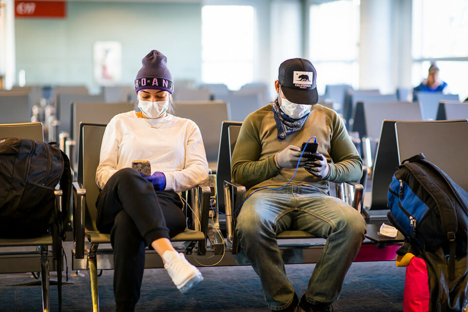 a man and woman sitting in chairs with masks on their faces