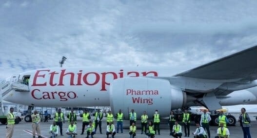 a group of people in yellow vests standing next to an airplane