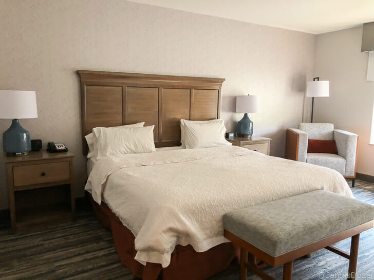 a bed with a bench and lamp in a hotel room