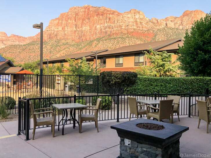 a patio with chairs and a fire pit in front of a mountain