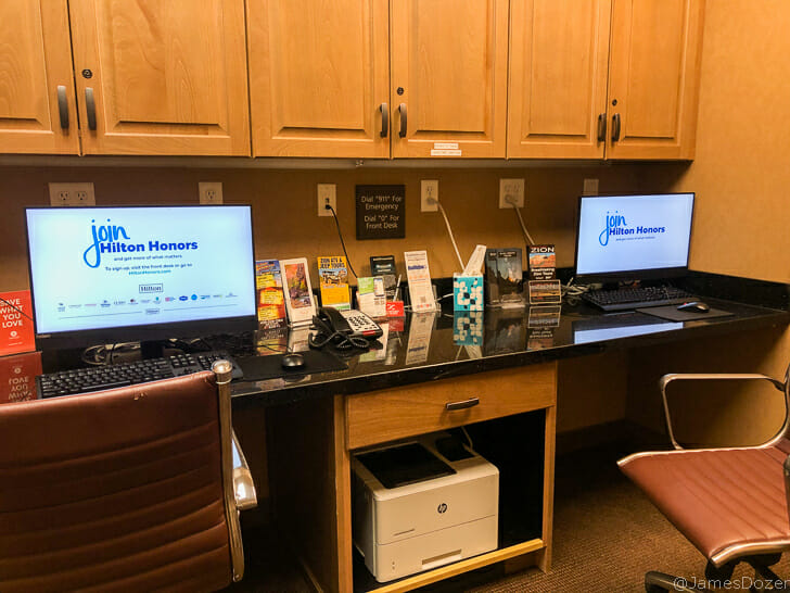 a desk with computers and a printer