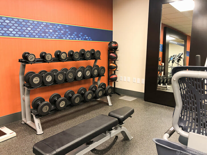 a room with a mirror and a rack of weights