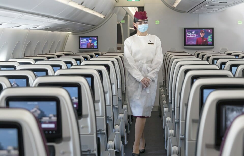 a woman wearing a mask and standing in a plane
