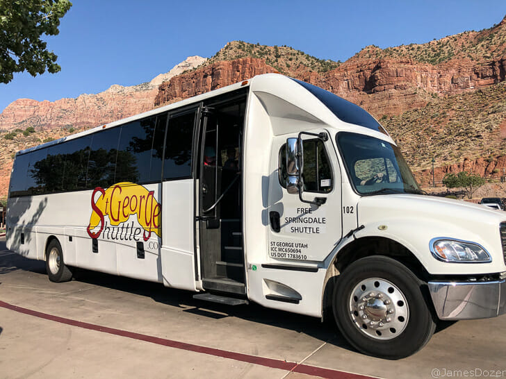 a shuttle bus parked in front of a rocky mountain