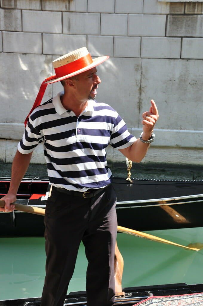 a man in a striped shirt and hat holding a paddle