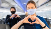 a woman wearing a face mask making a heart with her hands