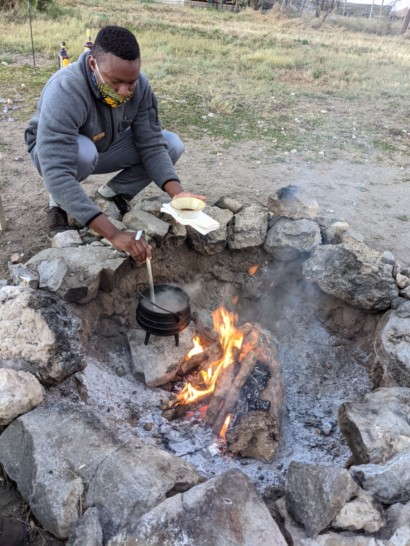 a man squatting over a fire pit