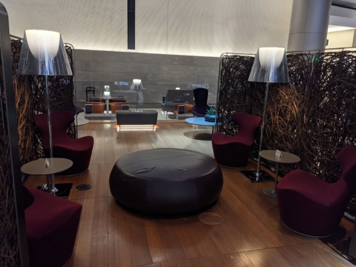 a room with a round black ottoman and floor lamps