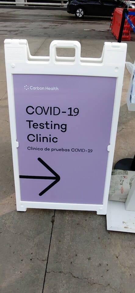 a sign with a arrow pointing to a covid-19 testing clinic