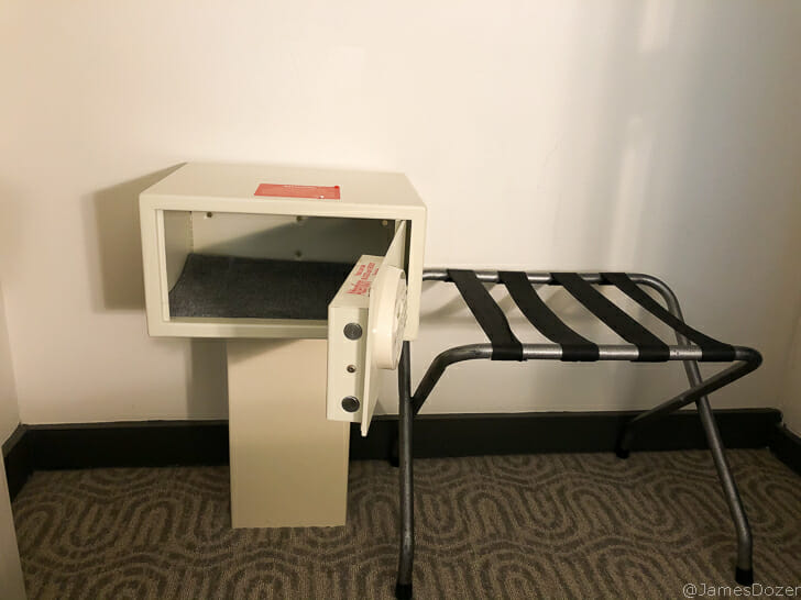 a small white safe with a red label and a black metal chair