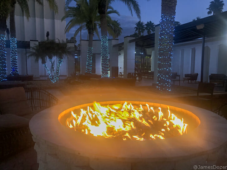 a fire pit with lights and palm trees in the background