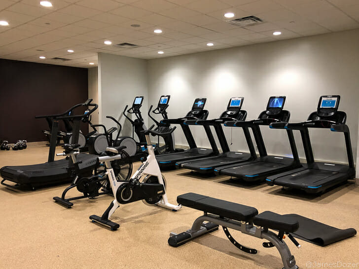 a room with exercise machines and a row of treadmills