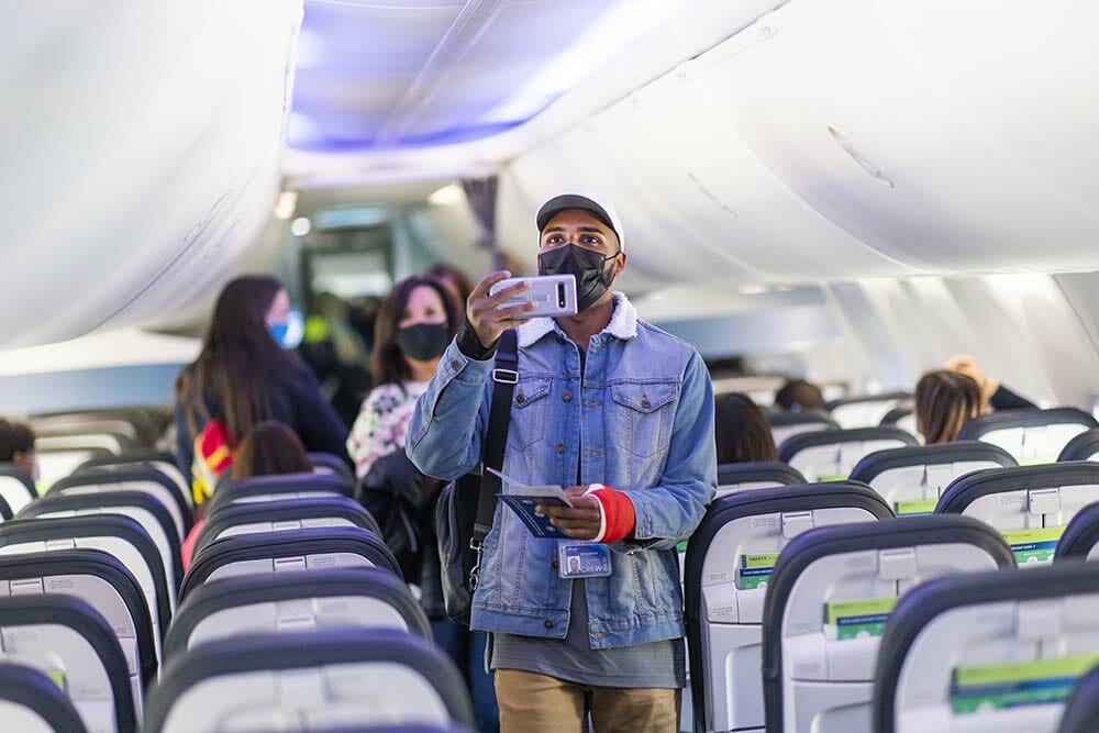 a man in a mask taking a selfie in an airplane