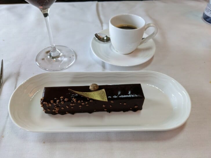 a chocolate dessert on a plate next to a cup of coffee