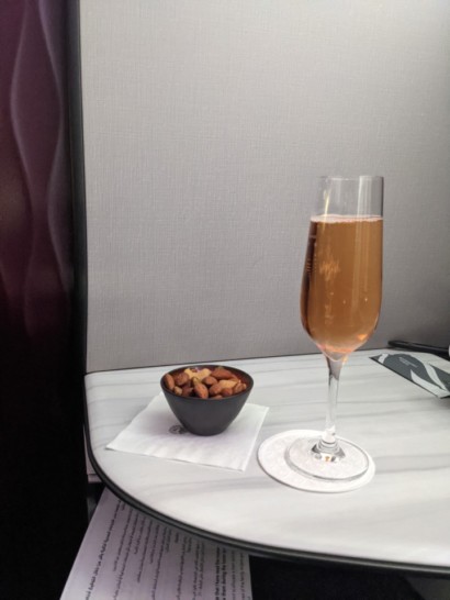 a glass of champagne and a bowl of nuts on a table