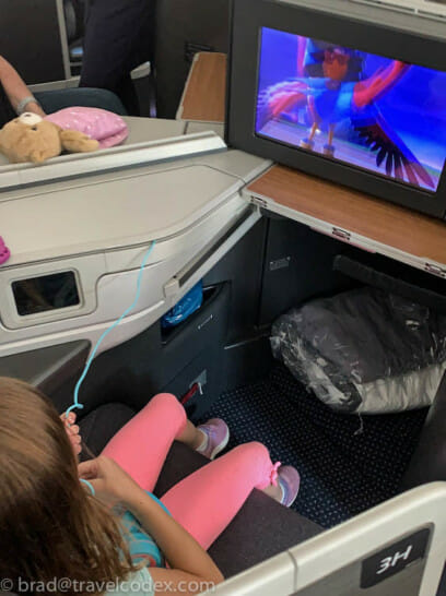 a child sitting in an airplane with a television