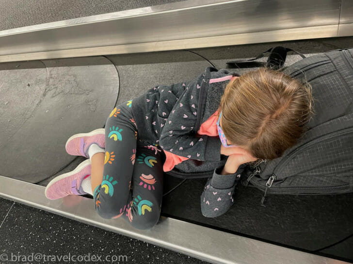 a girl lying on a luggage belt