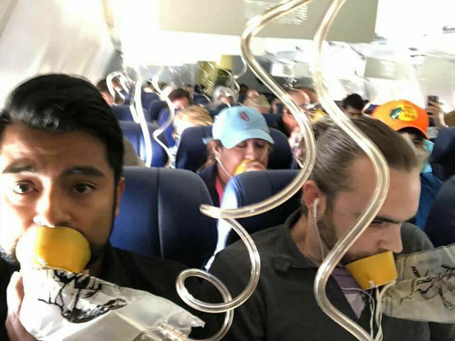 a group of people sitting on an airplane with tubes in their mouth
