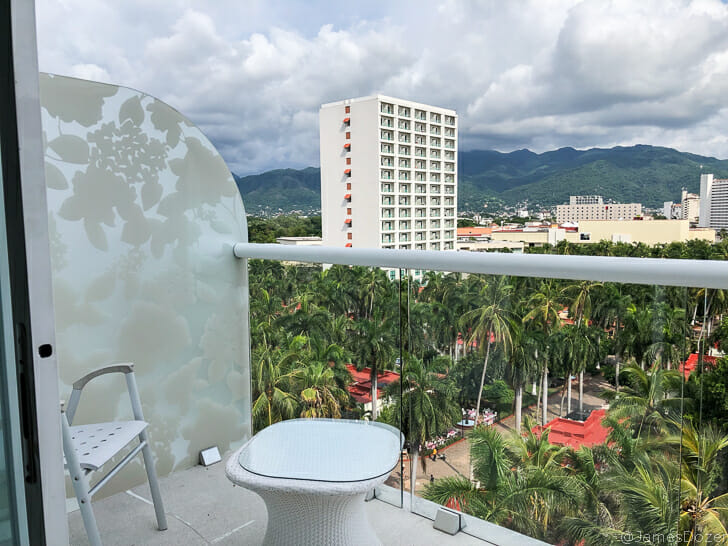a balcony with a white chair and a white railing with a city in the background