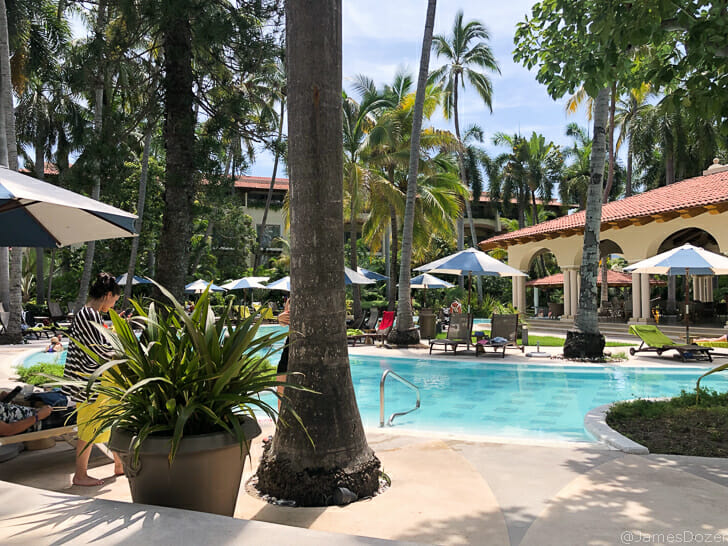 a pool with palm trees and a woman sitting in a chair