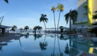 a pool with palm trees and a building