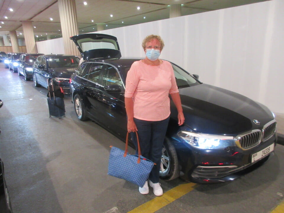 a woman wearing a face mask standing next to a car