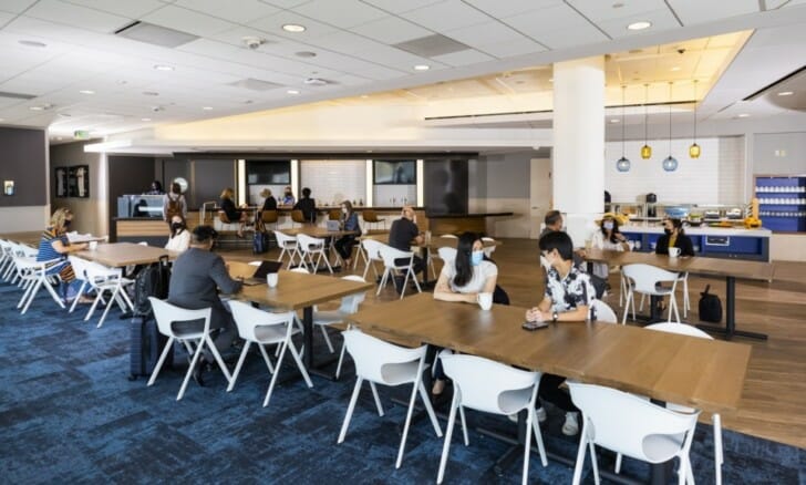 a group of people sitting at tables in a room with a blue carpet