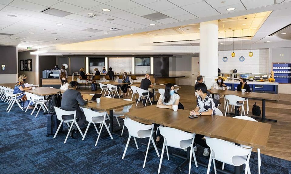 people sitting at tables in a room with people wearing face masks