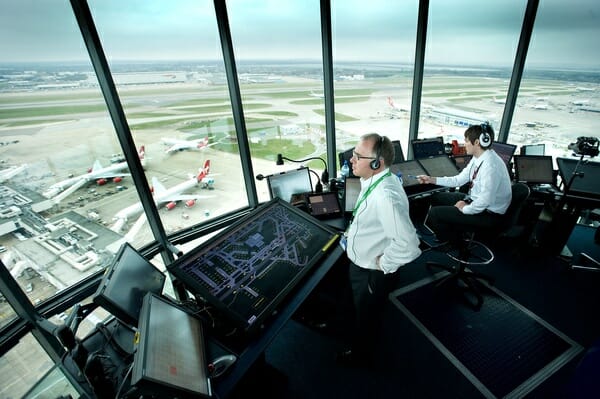 men in a control room with a large window