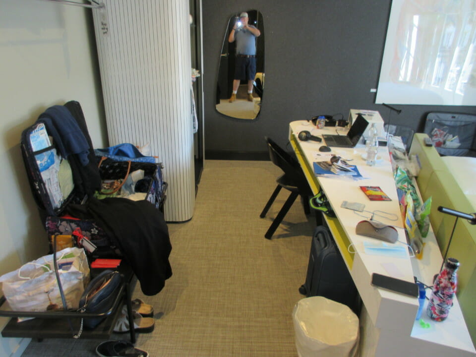 a room with a mirror and a desk with clutter