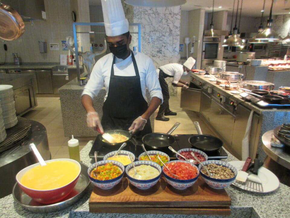 a man wearing a face mask and black apron cooking food in a kitchen