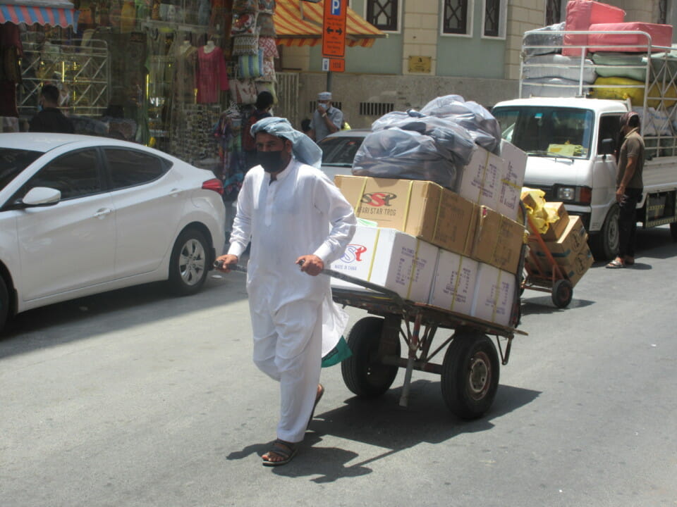 a man wearing a face mask and white outfit pushing a cart with boxes