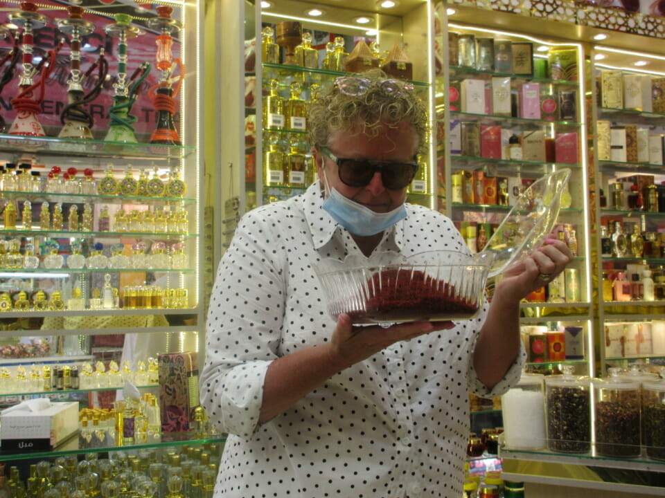 a woman holding a container of red powder