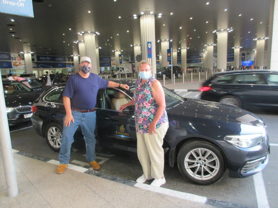 a man and woman standing next to a car