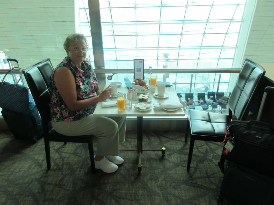 a woman sitting at a table with food and drinks