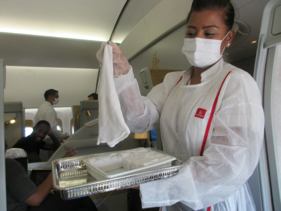 a woman wearing a mask and gloves holding a tray with food