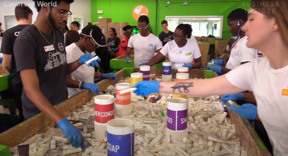 a group of people in gloves working on a table with containers