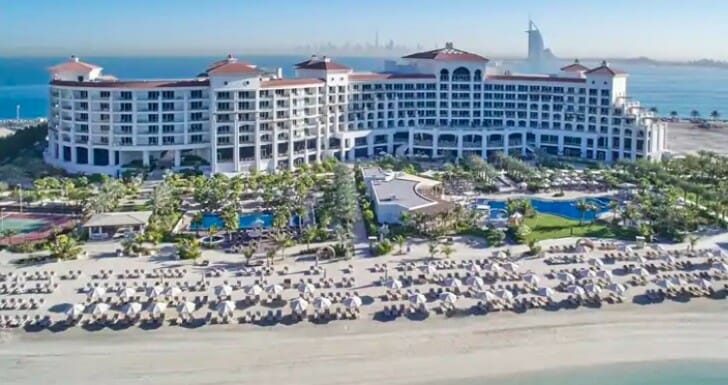 a large building with a beach and umbrellas