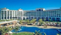 a large building with a pool and palm trees