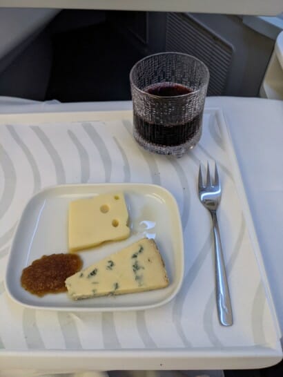 a plate of cheese and jam next to a glass of wine