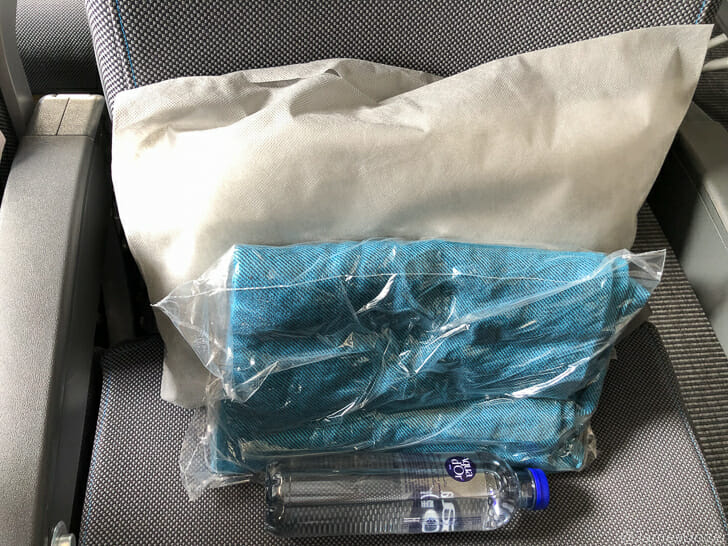 a plastic bag with a bottle and a white pillow on a seat