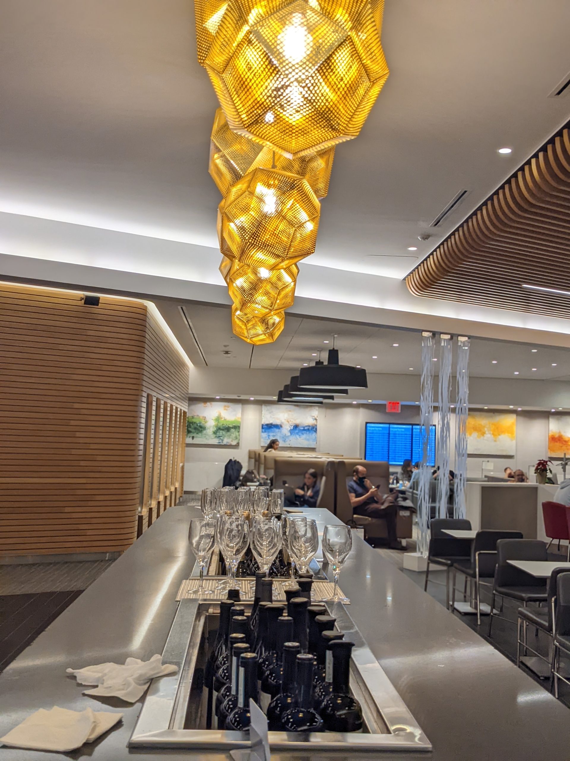 a bar with a row of glasses and a table with a group of people sitting in the background