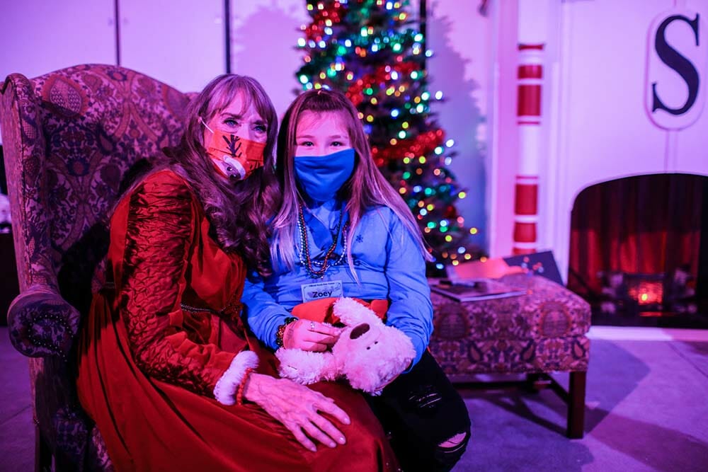 a woman and girl wearing face masks and sitting in a chair