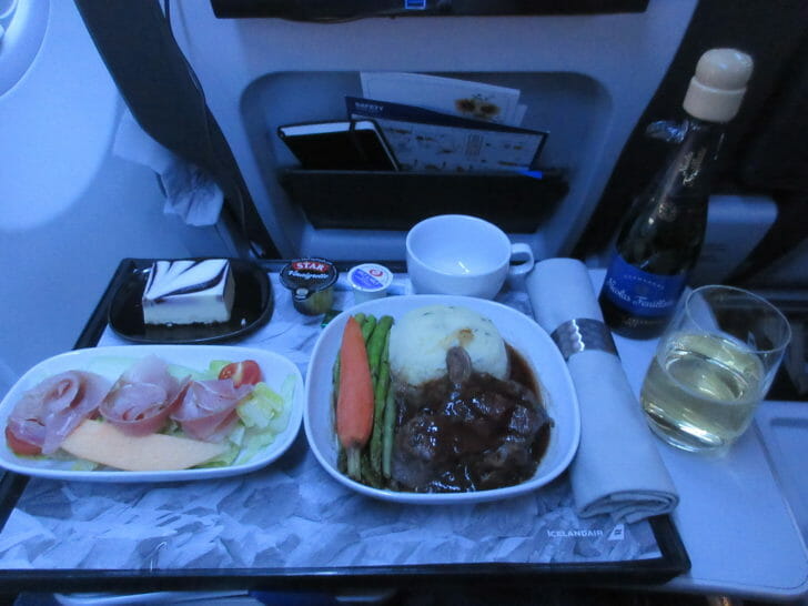 food on a tray with a drink and a glass of wine